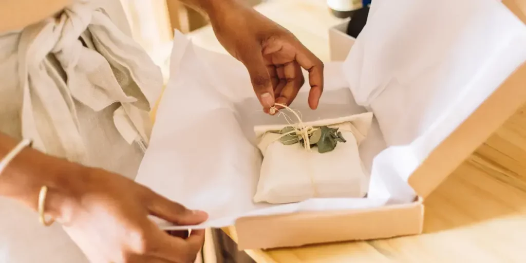 Closeup of hands packing a wrapped gift into a custom box