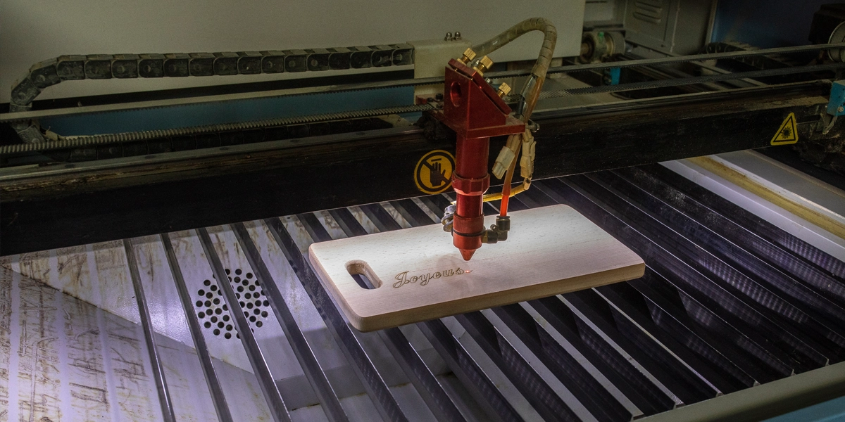 Close up of a laser engraving machine engraving into a wooden cutting board.