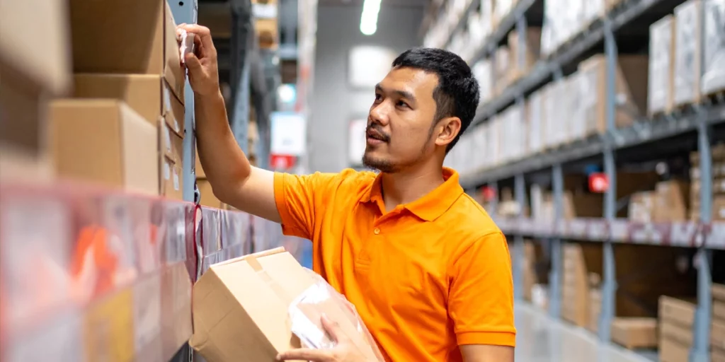 Warehouse employee picking an item from a warehouse shelf.