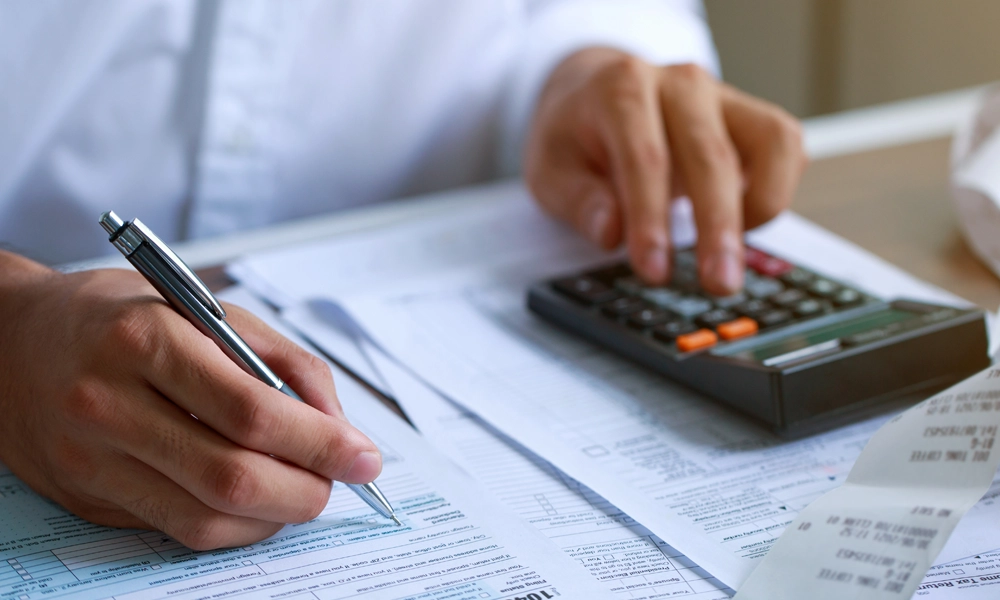 Business person using a calculator to determine tax values.