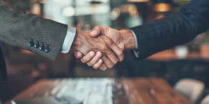 Two Hands reaching across a table, shaking hands.